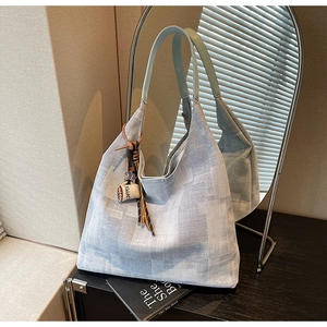 Detail showing the woven texture of the tote bag with coffee cup charm and leather handles