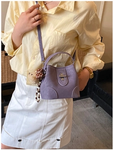 Detail of purple minimalist bucket bag with silver twist lock and cute bear charm