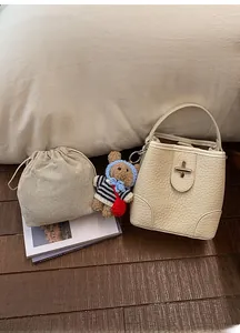 Detail of beige bucket bag with drawstring liner and a small teddy bear charm accessory