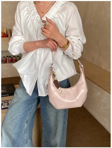 Detail of light pink crescent bag with quilted design, chocolate charm and silk scarf