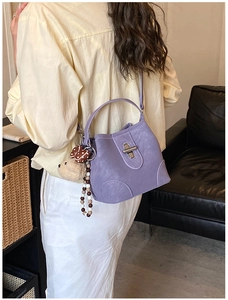 Detailed view of a purple leather bucket bag with a cute bear charm and rotating metal lock