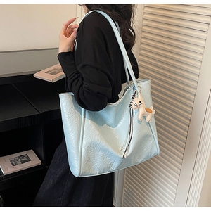 Detail of light blue pleated tote bag featuring a cute beige horse charm accessory