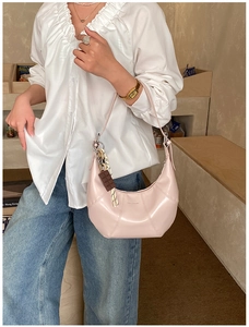 Detail of light pink hobo bag with unique stitching and chocolate-shaped charm