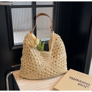 Detail of hollow woven beach bag with brown leather handles and yellow tulip accent
