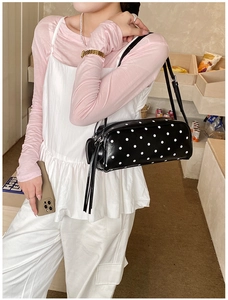 Detailed shot of black polka dot underarm bag with long fringe and slim shoulder strap