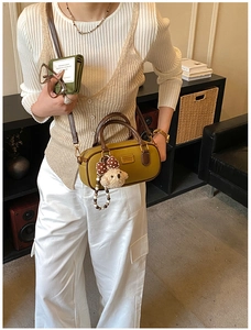 Macro shot of ginger yellow cylindrical bag with brown handle and plush bear charm