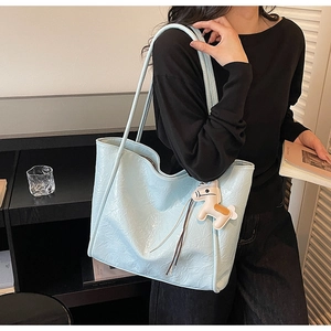 Light blue tote bag with pleated texture and horse charm in a cozy lifestyle setting