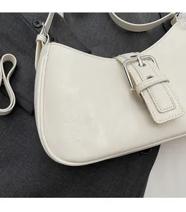 Detail of creamy white textured leather handbag with silver metallic buckle on grey background