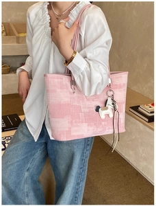 Detailed shot of pink textured bucket bag with a white horse charm on a shoulder strap