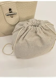 Detail of detachable woven inner pouch with drawstring and cream lychee leather bucket bag