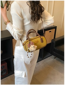 Detail of yellow Boston style handbag with brown handles and cute puppy charm on a model