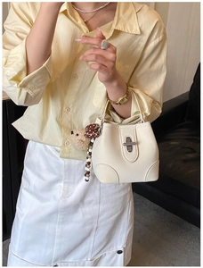 Close-up of white mini bucket bag with silver twist lock and cute bear charm pendant
