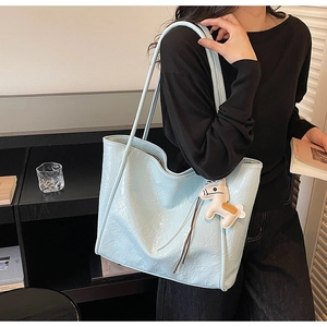Detail of light blue pleated tote bag with horse charm on a stylish shoulder strap