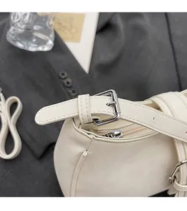 Detail of creamy white lychee grain leather handbag with silver metallic buckle hardware