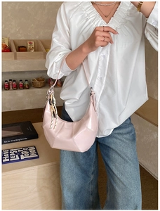 Detail of pink crescent leather bag featuring contrast braided knot and Love & Peace print