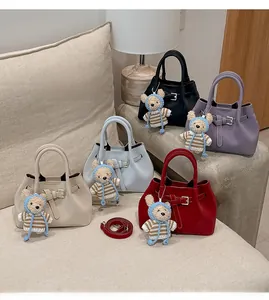 Close-up of retro bucket bags in five colors with cute bear charms on a cozy sofa