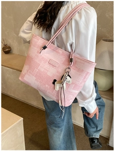 Pink tote bag with pixel print and tassel horse charm shown in a cozy indoor setting