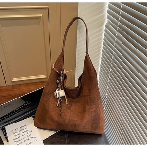 Detail of tan woven tote bag with leather strap and unique coffee cup charm accent