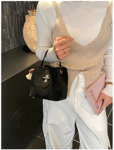 Close-up of black textured bucket bag with silver twist lock and mushroom charm