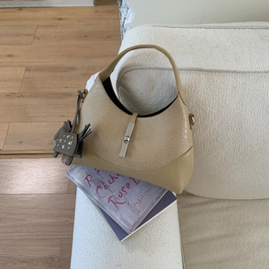 Detailed view of beige hobo bag leather texture with silver clasp and horse charm