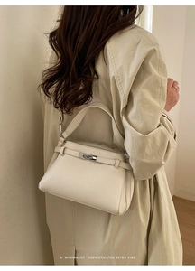 Detail view of cream pebble leather texture and silver metallic twist lock closure
