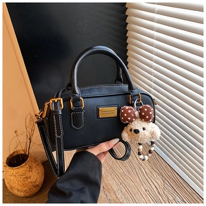 Detail of black pebbled leather handbag featuring white contrast stitching and gold hardware