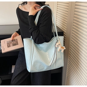 Detail of light blue tote bag with pleated leather texture and a small horse charm