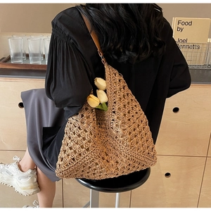 Detailed close-up of a brown woven straw tote bag with elegant leather shoulder strap