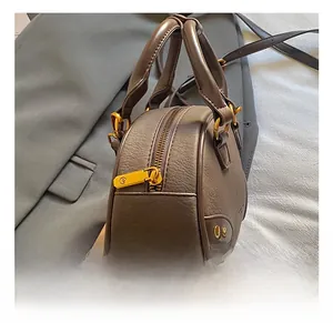 Detail of dark brown pebble leather pillow bag with gold hardware and side rivets