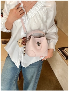 Pink bucket bag with silver lock and teddy charm shown on a casual chic outfit