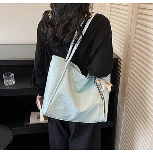 Detail view of a large light blue tote bag featuring a glossy wrinkled leather texture