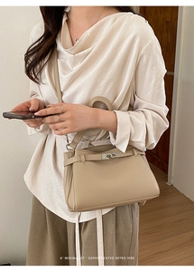 Detailed view of beige lychee leather texture and silver buckle on the Kelly handbag