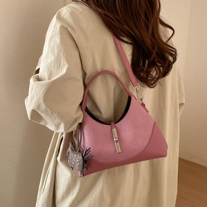 Detail view of pink leather half-moon bag with silver buckle and cat charm on model