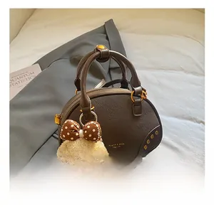 Detail of dark brown leather bowling bag with golden hardware and cute puppy charm