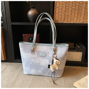 Detail of blue pixel texture tote bag with a cream horse charm in a vintage setting