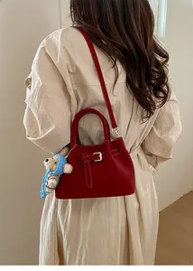 Model wearing a vintage burgundy crossbody bucket bag with a cute bear charm accessory