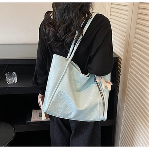 Detail of light blue tote bag featuring a wrinkled texture and a white horse charm accessory