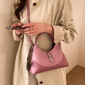 Detail shot of a pink crescent leather handbag with silver metallic buckle and shoulder strap
