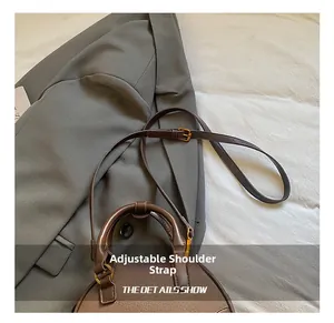 Detail view of brown pebble leather handbag with adjustable slim shoulder strap and gold buckle