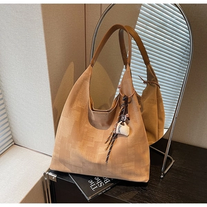 Detail of khaki canvas tote bag with brown leather handles and coffee cup pendant charm