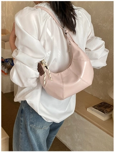 Detail of pink croissant shoulder bag with woven pendant and chocolate charm