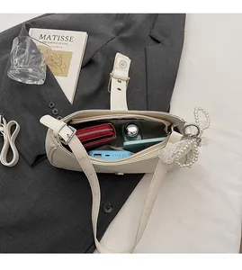 Detail view of the spacious inner compartment with zip pocket in a cream PU shoulder bag