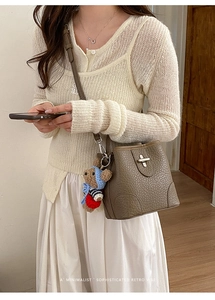 Detail of brown lychee texture bucket bag with cute bear charm and silver metal closure