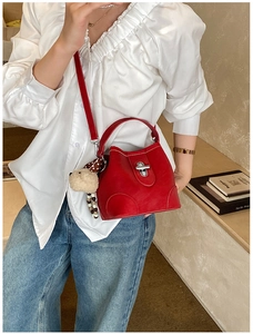 Detail view of red leather bucket bag with silver twist lock and plush animal charm