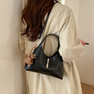 Detail of black crescent shoulder bag with silver hardware on a trench coat model