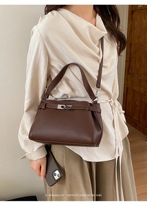 Detailed macro view of dark brown Togo leather texture and silver buckle on the handbag