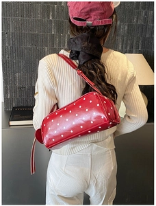 Detail of red cylindrical polka dot shoulder bag with stylish fringe zipper and leather strap