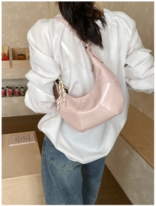 Pink crescent shoulder bag with knotted details shown in a lifestyle indoor setting