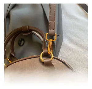 Close-up of premium gold-tone metal hook and textured brown leather on a crossbody bag