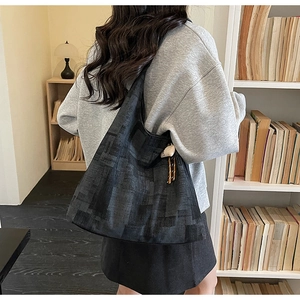 Detail of black tote bag with geometric pattern and white shell charm accessory